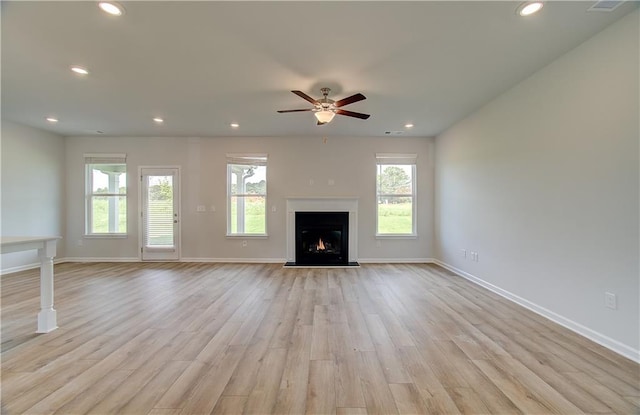 unfurnished living room featuring a wealth of natural light, light hardwood / wood-style flooring, and ceiling fan