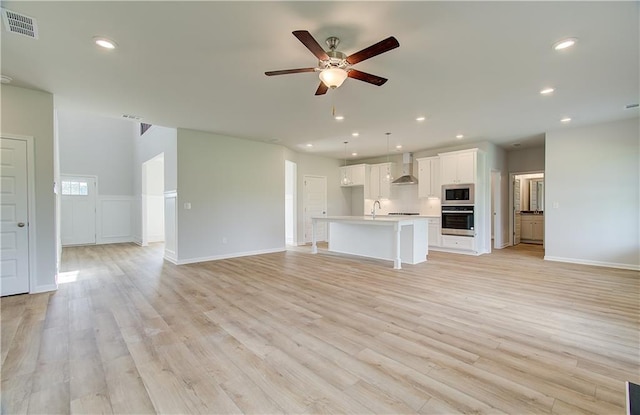 unfurnished living room featuring ceiling fan, sink, and light hardwood / wood-style flooring