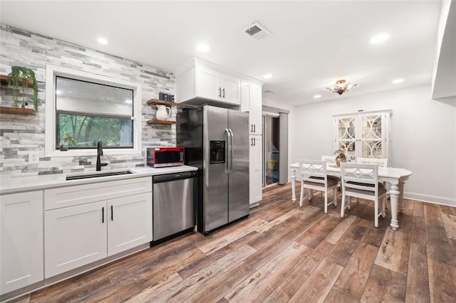 kitchen featuring stainless steel appliances, a sink, open shelves, tasteful backsplash, and white cabinetry