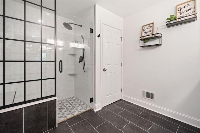 bathroom with a shower stall, tile patterned flooring, and baseboards