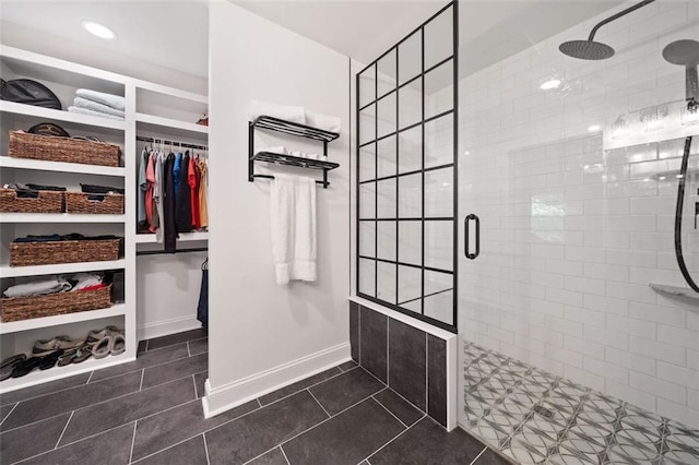 full bath with a stall shower, tile patterned flooring, a walk in closet, and baseboards