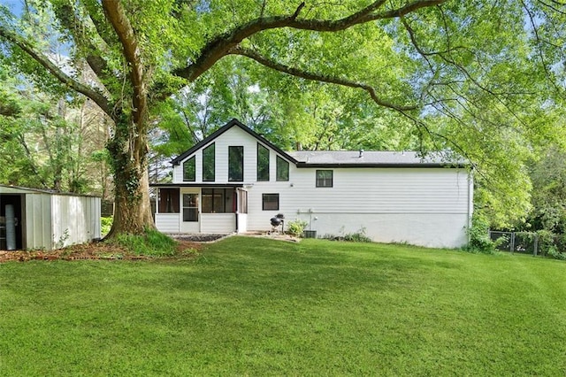 back of house with a sunroom, a yard, and an outbuilding