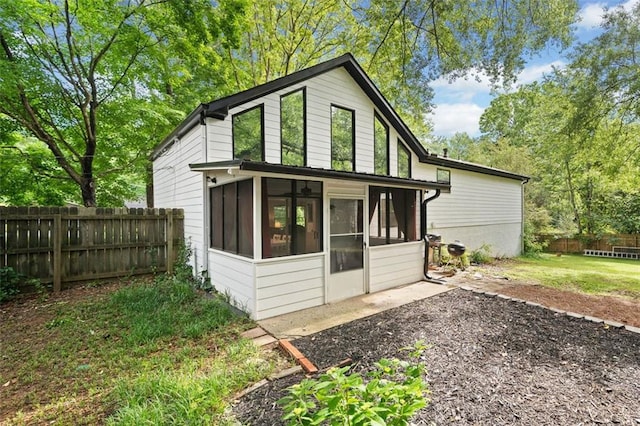 rear view of house featuring a sunroom and fence