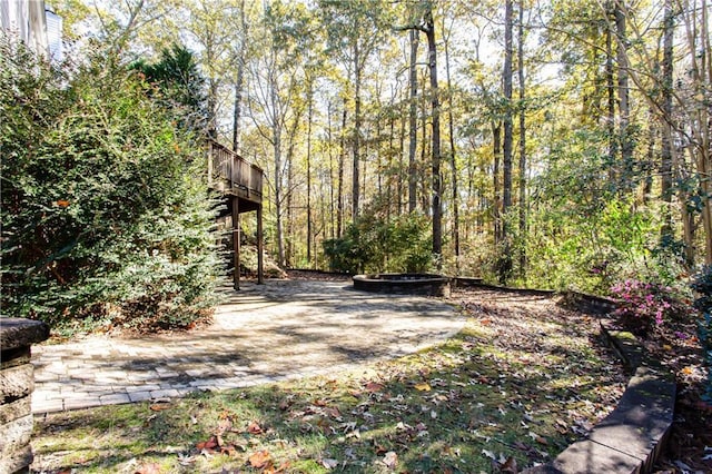 view of yard with an outdoor fire pit and a view of trees