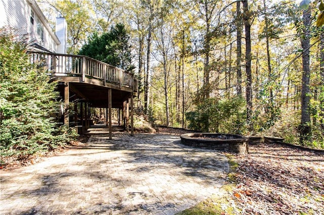 view of yard with a forest view, an outdoor fire pit, and a wooden deck