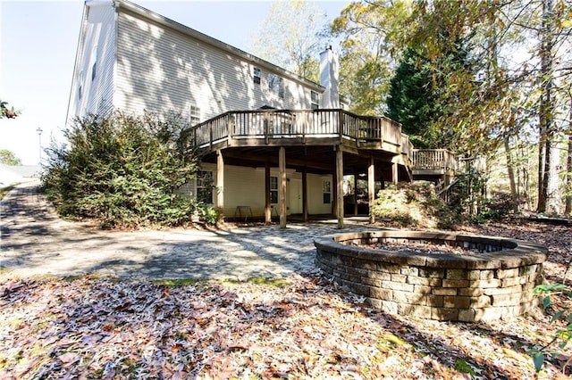 rear view of house with a deck, an outdoor fire pit, and a chimney