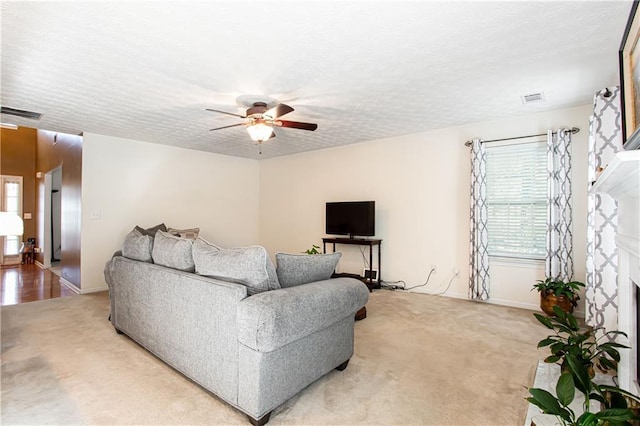 living area with a wealth of natural light, visible vents, a fireplace, and a textured ceiling