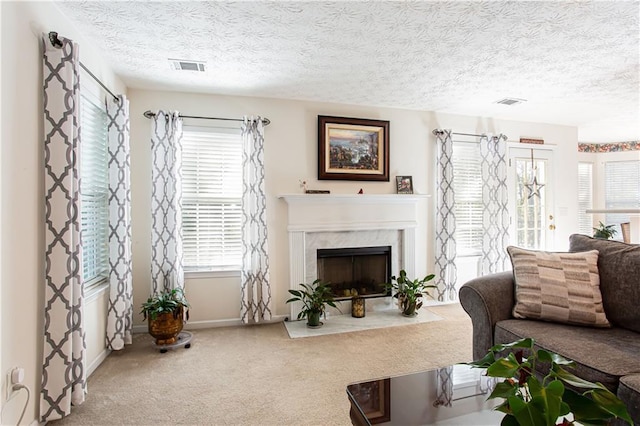 living room with plenty of natural light, a premium fireplace, visible vents, and carpet flooring