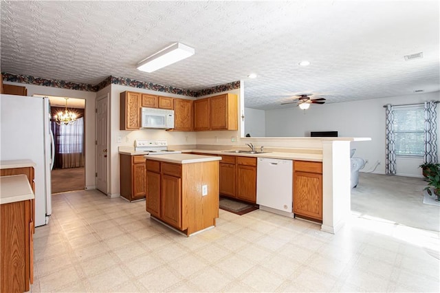 kitchen with a peninsula, white appliances, visible vents, and light floors