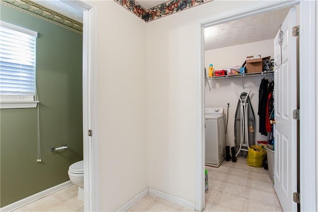 bathroom with toilet, a textured ceiling, washer / dryer, baseboards, and tile patterned floors