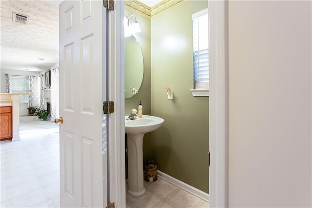 bathroom with visible vents, a textured ceiling, baseboards, and tile patterned floors