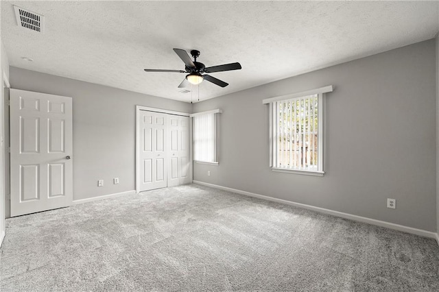 unfurnished bedroom featuring ceiling fan, carpet, a textured ceiling, and a closet