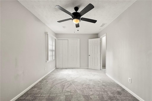 unfurnished bedroom featuring ceiling fan, carpet floors, a closet, and a textured ceiling