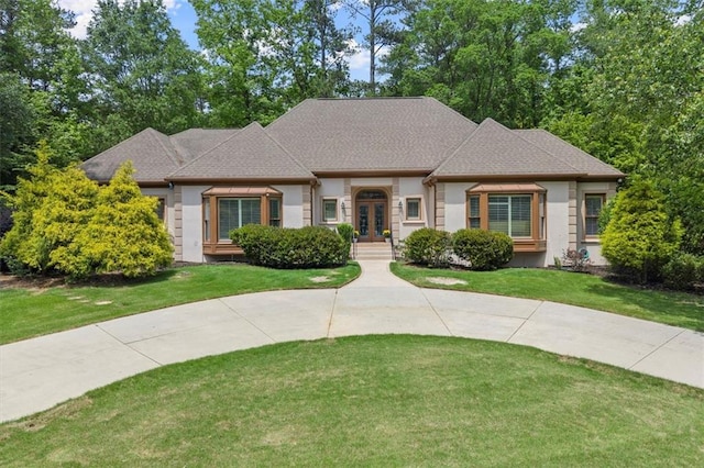 view of front of property with french doors, a front yard, stucco siding, and a shingled roof