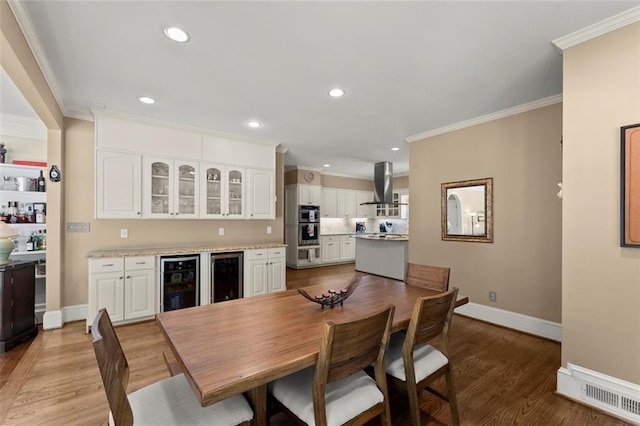dining room with beverage cooler, crown molding, baseboards, wood finished floors, and recessed lighting