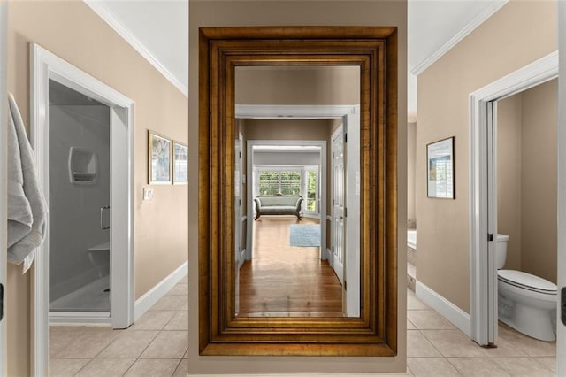 hallway featuring light tile patterned floors, baseboards, and crown molding
