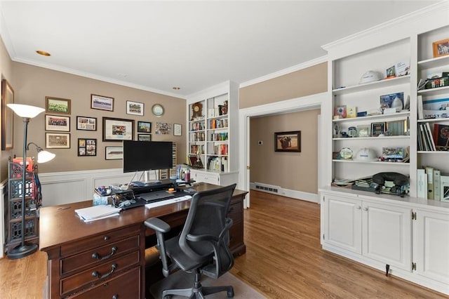 office area with wood finished floors, ornamental molding, and built in features