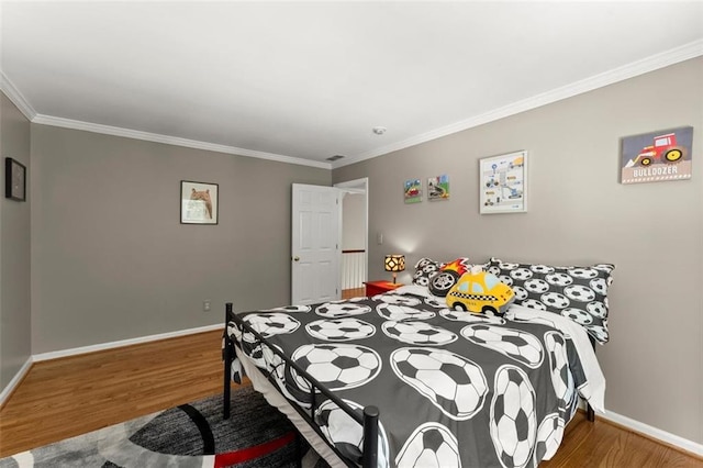 bedroom featuring wood finished floors, ornamental molding, and baseboards
