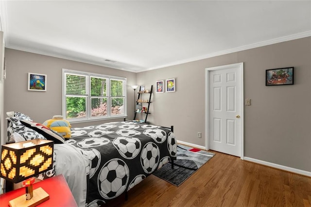 bedroom featuring wood finished floors, ornamental molding, and baseboards