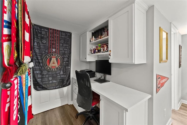 office space featuring built in desk, wood finished floors, and baseboards