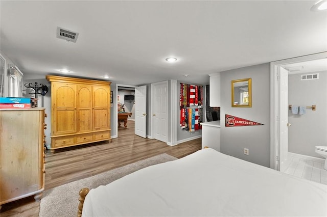 bedroom featuring baseboards, recessed lighting, wood finished floors, and ensuite bath