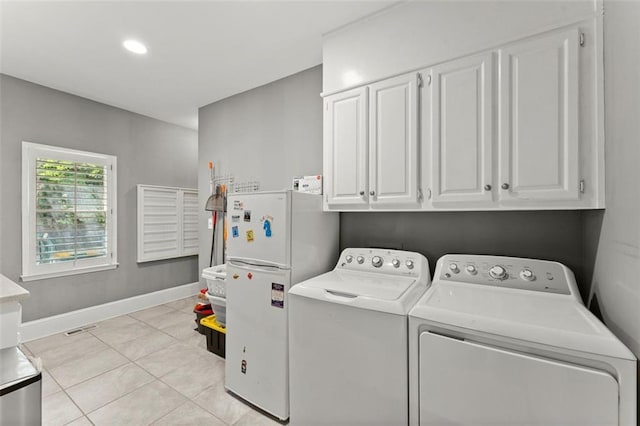 laundry area with separate washer and dryer, cabinet space, light tile patterned floors, and baseboards