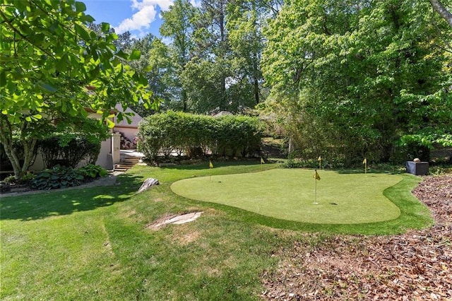 view of home's community featuring an area to practice putting and a lawn
