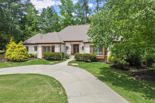 view of front of home with french doors, a front yard, stucco siding, and a shingled roof