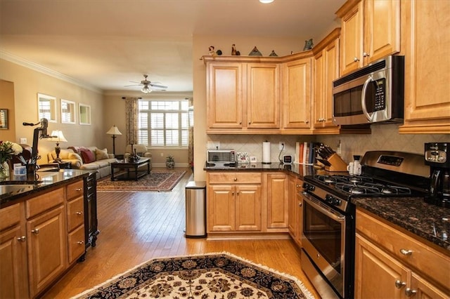 kitchen featuring ceiling fan, light hardwood / wood-style flooring, crown molding, dark stone counters, and appliances with stainless steel finishes