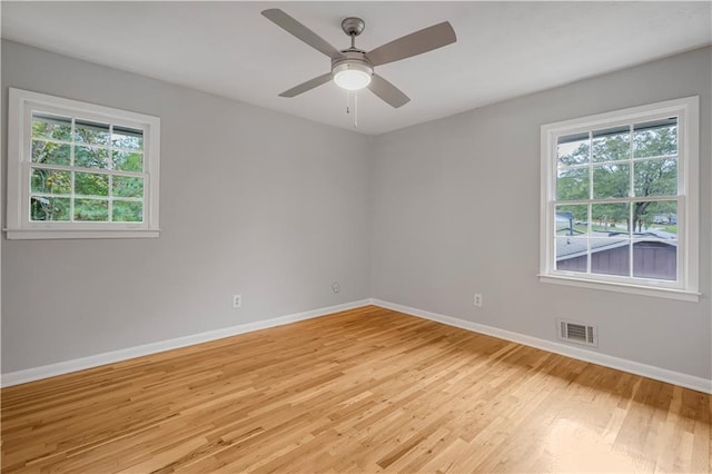 spare room with a ceiling fan, visible vents, light wood-style flooring, and baseboards