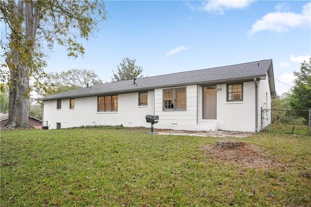 back of house featuring brick siding, a shingled roof, fence, a yard, and crawl space