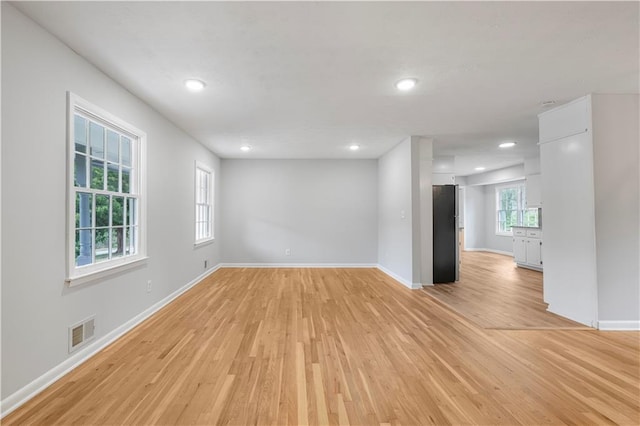 spare room with light wood-style flooring, visible vents, and baseboards