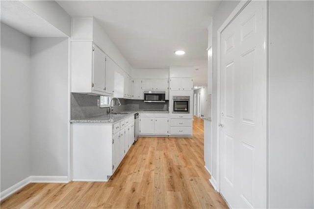 kitchen with white cabinets, light wood-type flooring, stainless steel appliances, and a sink