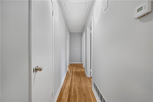 corridor with light wood-style floors, attic access, visible vents, and baseboards