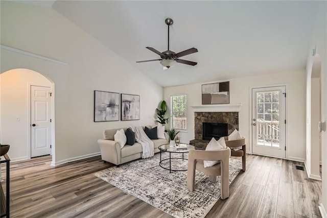 3290 Spincaster Way, Loganville, GA 30052 - living area featuring a ceiling fan, arched walkways, wood finished floors, a stone fireplace, and high vaulted ceiling