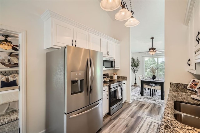 3290 Spincaster Way, Loganville, GA 30052 - kitchen with appliances with stainless steel finishes, a ceiling fan, white cabinets, light wood-style flooring, and dark stone countertops
