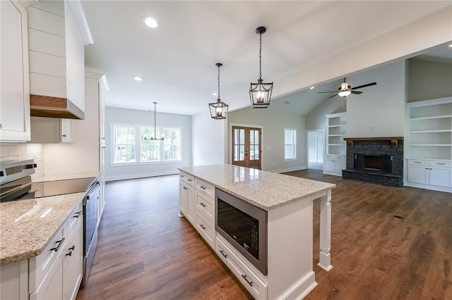 82 Lexie Ct, Rockmart, GA 30153 - kitchen featuring stainless steel appliances, vaulted ceiling, a fireplace, dark wood finished floors, and white cabinetry