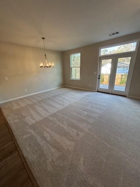 spare room featuring carpet floors and an inviting chandelier