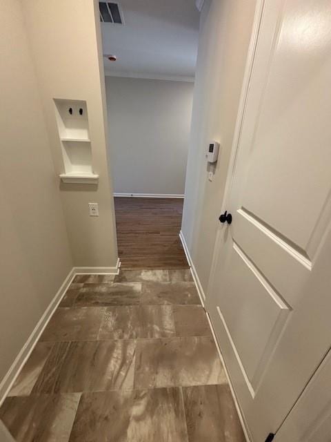 corridor with dark hardwood / wood-style flooring and ornamental molding