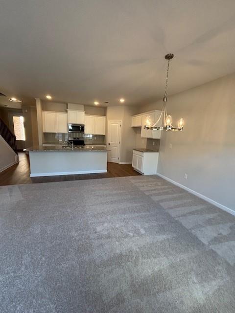 unfurnished living room with sink and an inviting chandelier