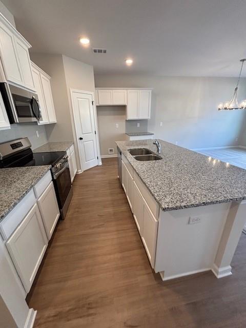 kitchen with a kitchen island with sink, white cabinetry, sink, and appliances with stainless steel finishes