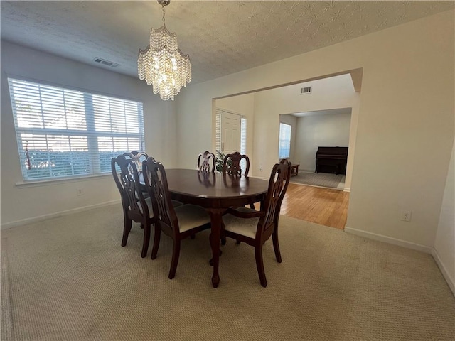 dining room with carpet flooring, a notable chandelier, and a textured ceiling