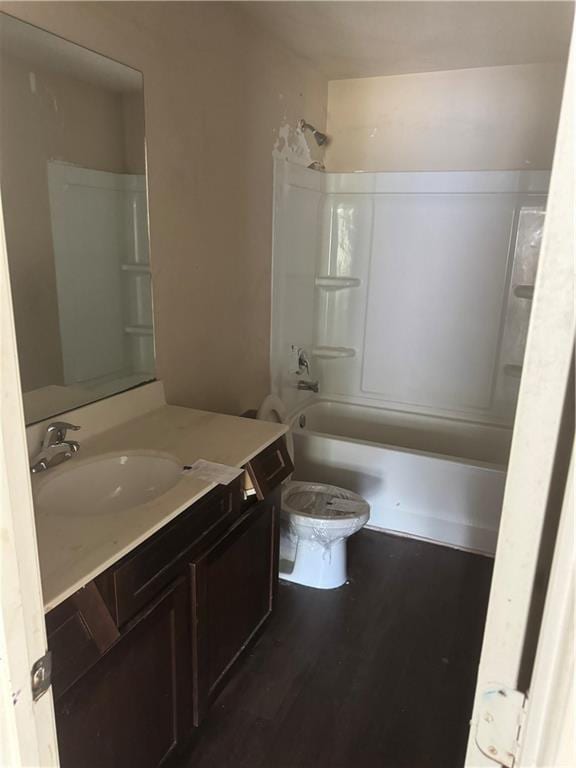 full bath featuring toilet, washtub / shower combination, vanity, and wood finished floors