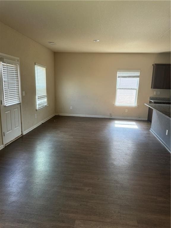 unfurnished living room featuring dark wood finished floors and baseboards