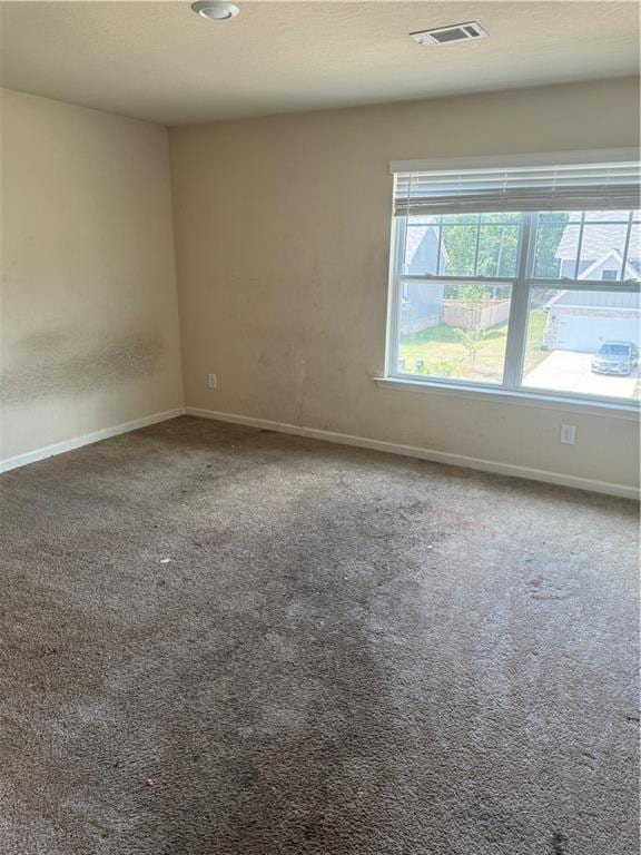 carpeted spare room with baseboards and visible vents