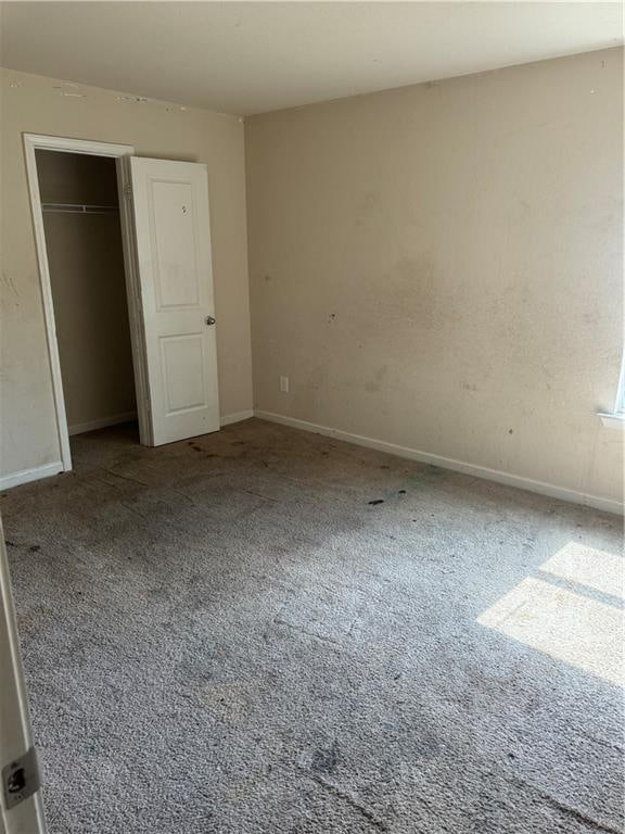 unfurnished bedroom with a closet, baseboards, and carpet floors