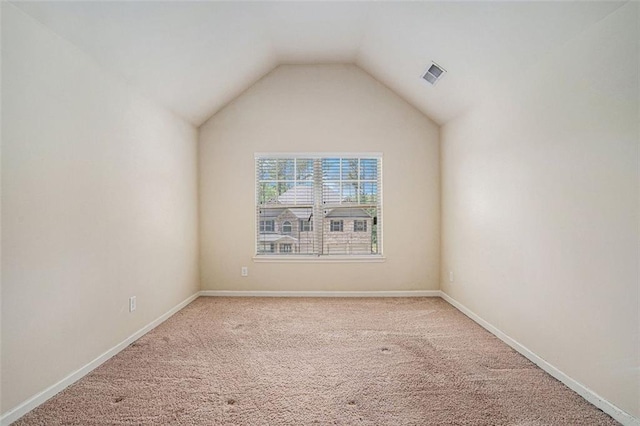 carpeted empty room with vaulted ceiling