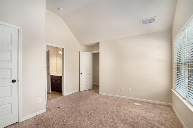 unfurnished bedroom with light carpet, connected bathroom, and lofted ceiling