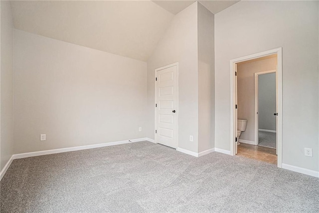 unfurnished bedroom with carpet flooring, ensuite bathroom, and high vaulted ceiling