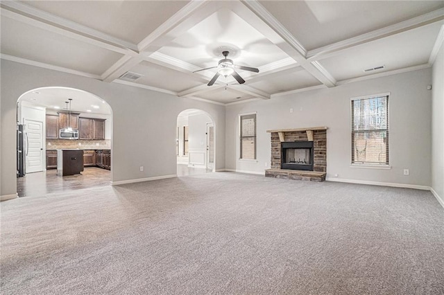 unfurnished living room with a stone fireplace, ceiling fan, light carpet, and coffered ceiling